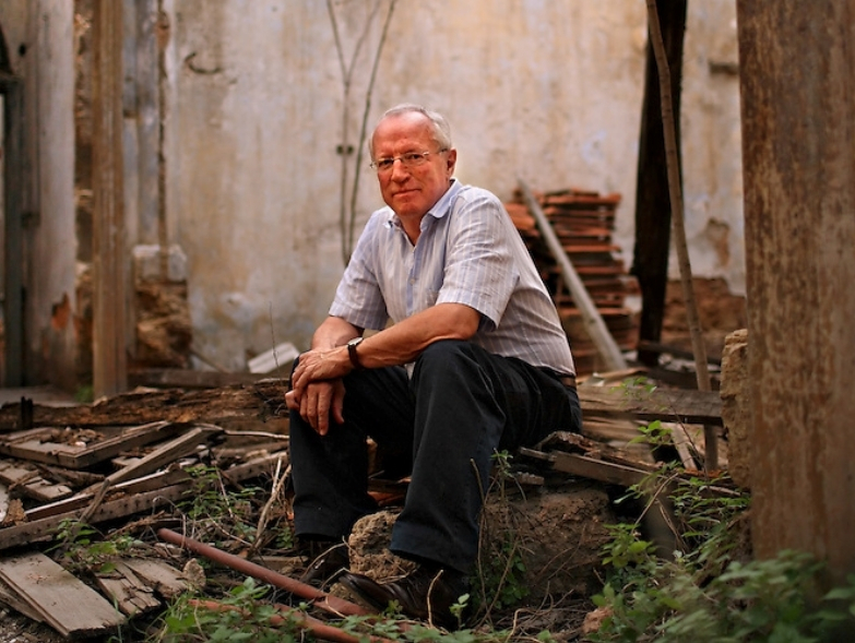 Journalist Robert Fisk sitting in the the rubble of a ruined building